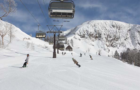 雪山を背景にしたゲレンデとスノーボーダー