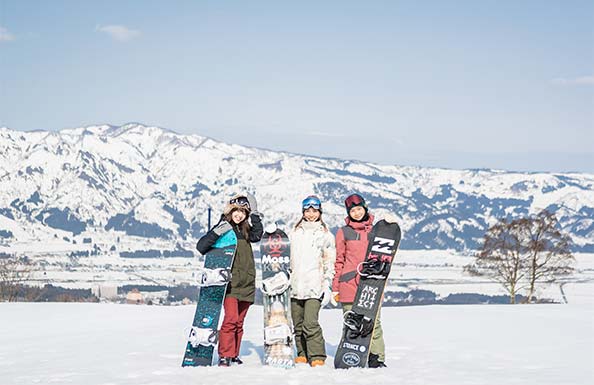 雪山を背景に映る女性３人組のスノーボーダー