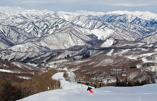 雪山を背景に颯爽と滑るスノーボーダー
