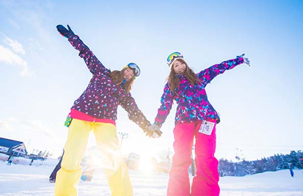 雪景色の中でポーズを取る女性スノーボーダー２人組